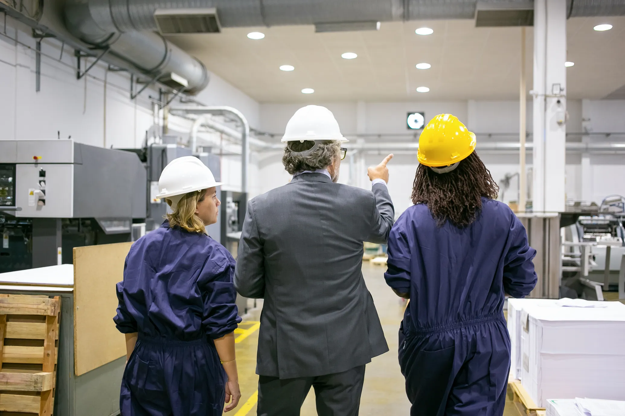 Employees in hard hats walking on a plant floor